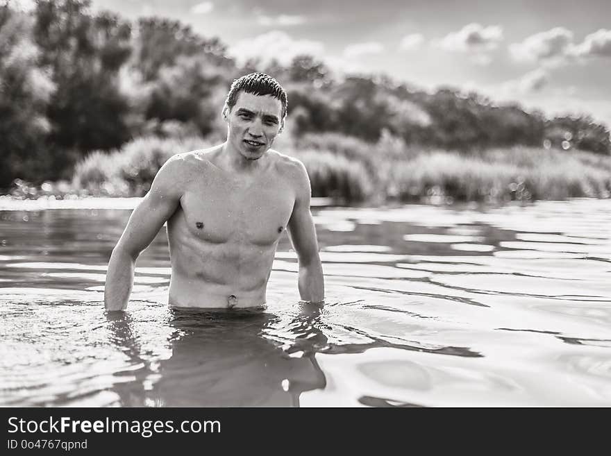Portrait of a handsome young man in the water. Monochrome old style photo.