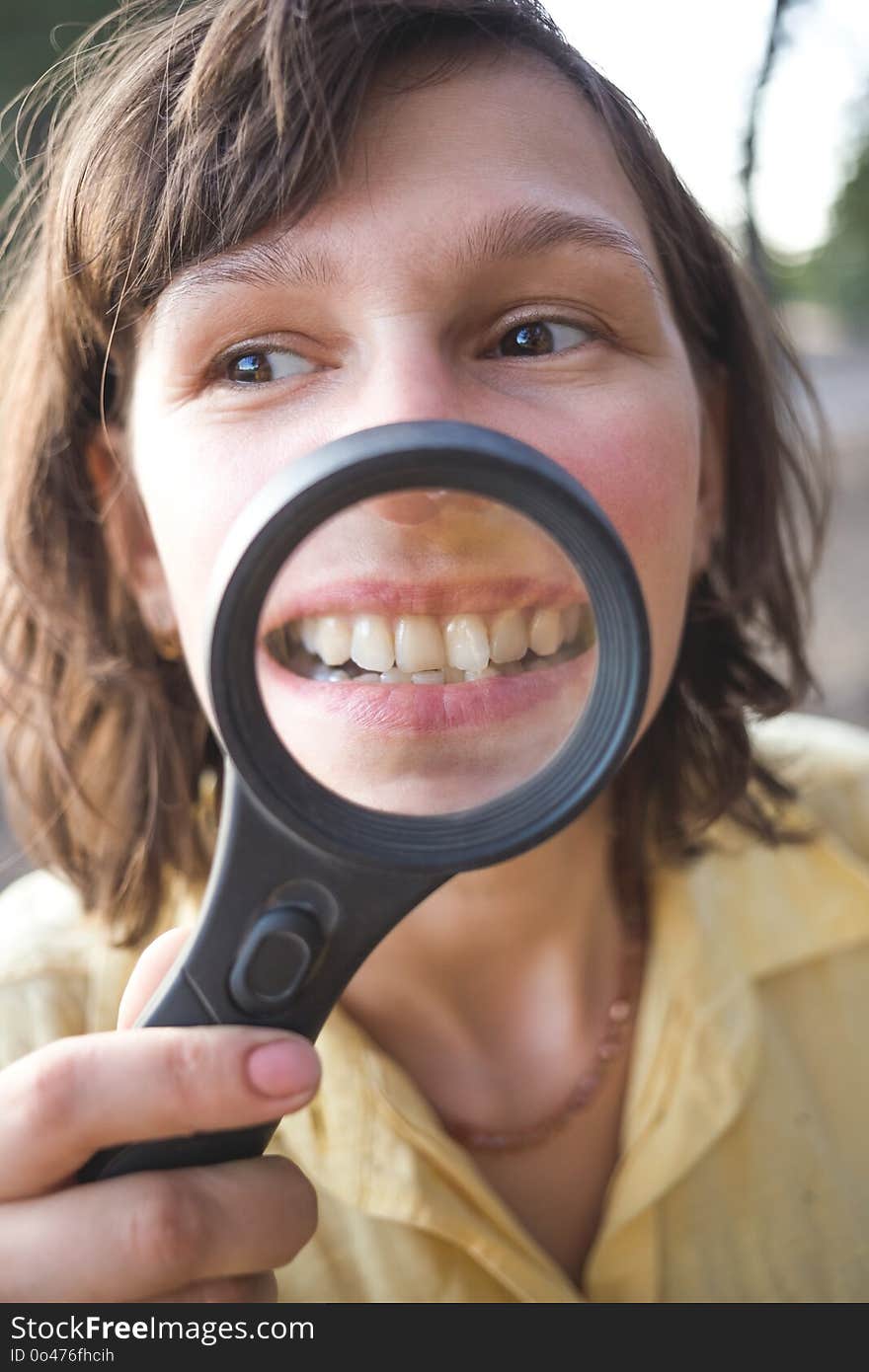 Woman with magnifier shows her crooked teeth