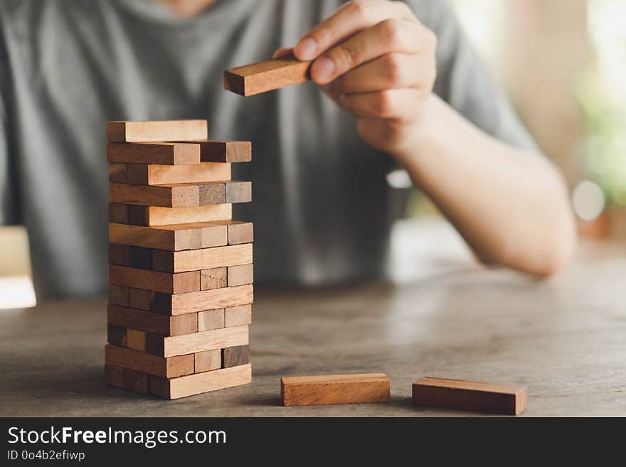 The risk will happen.Hand of engineer playing a blocks wood game on wood table vintage tone. architectural project .as background business concept with copy space