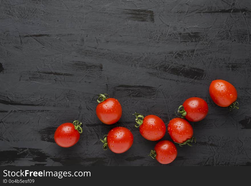 Delicious fresh tomatoes and salt on black table