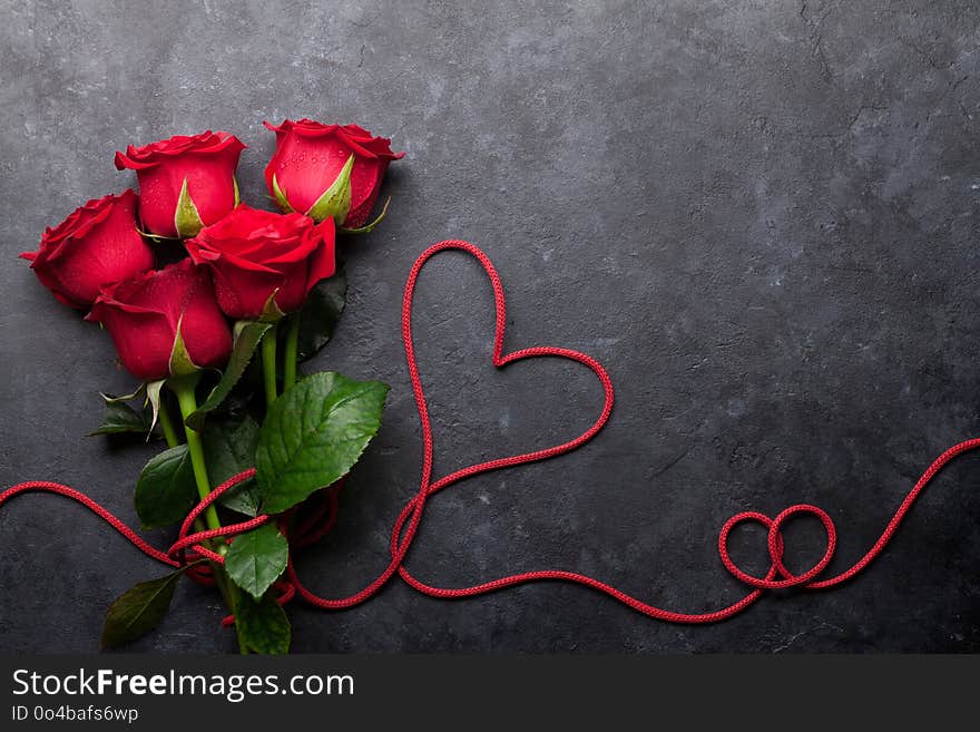 Valentine`s day greeting card with red rose flowers bouquet on stone background. Top view with space for your greetings. Valentine`s day greeting card with red rose flowers bouquet on stone background. Top view with space for your greetings