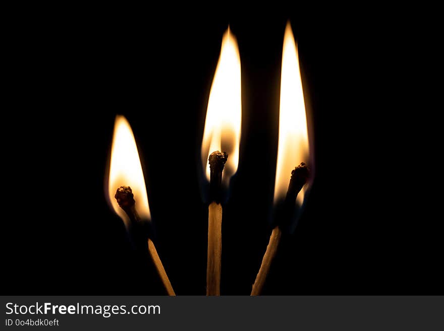 Three burning matches in the dark close up