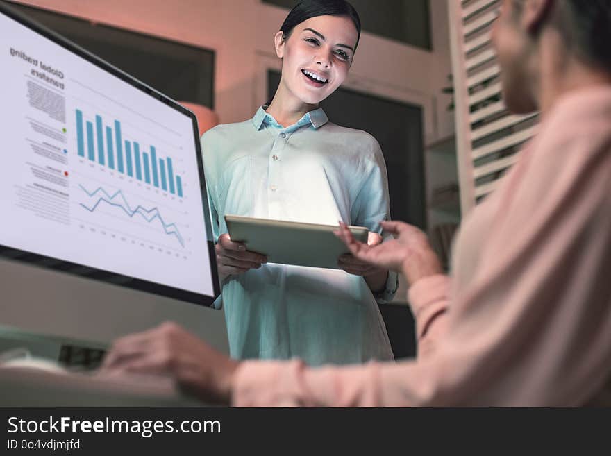 Give it to me. Competent business person sitting at her workplace and stretching arm while talking tablet. Give it to me. Competent business person sitting at her workplace and stretching arm while talking tablet