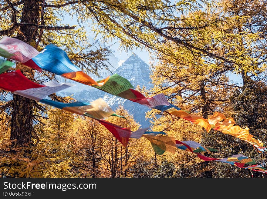 Sacred Xiannairi mountain with colorful prayer flags blowing in autumn forest