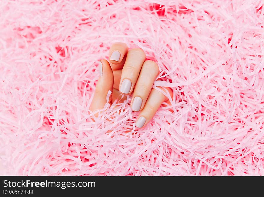 Beautiful female hands with trendy stylish manicure on pink background. Multicolored Bottles of nail polish. Top view, flat lay