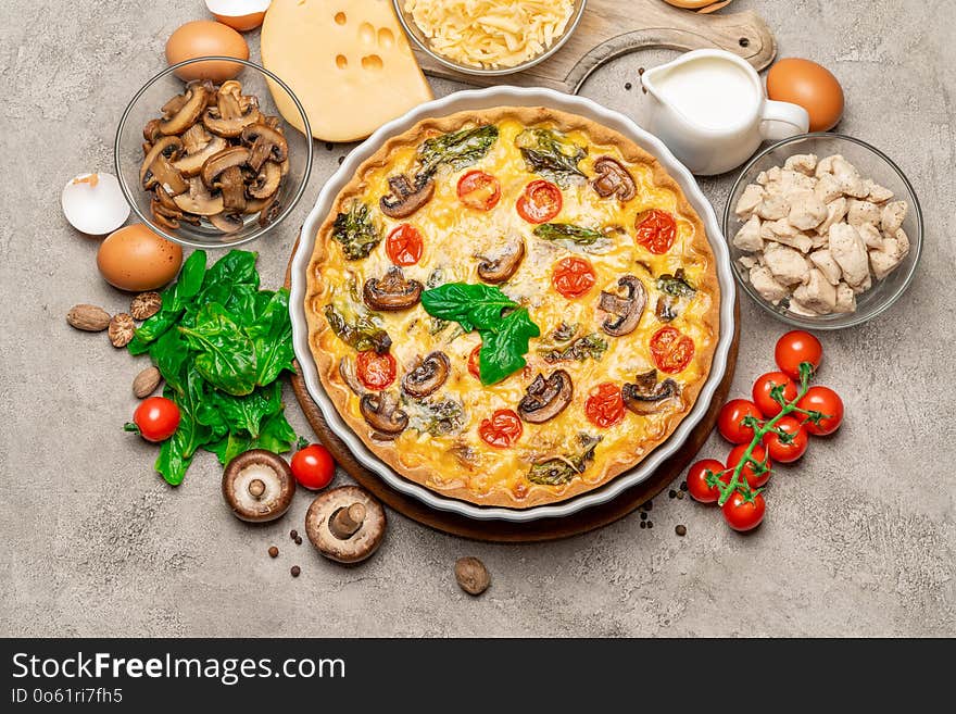 Baked homemade quiche pie with tomato, chcken and mushrooms in ceramic baking form, eggs and cream on white background. Baked homemade quiche pie with tomato, chcken and mushrooms in ceramic baking form, eggs and cream on white background