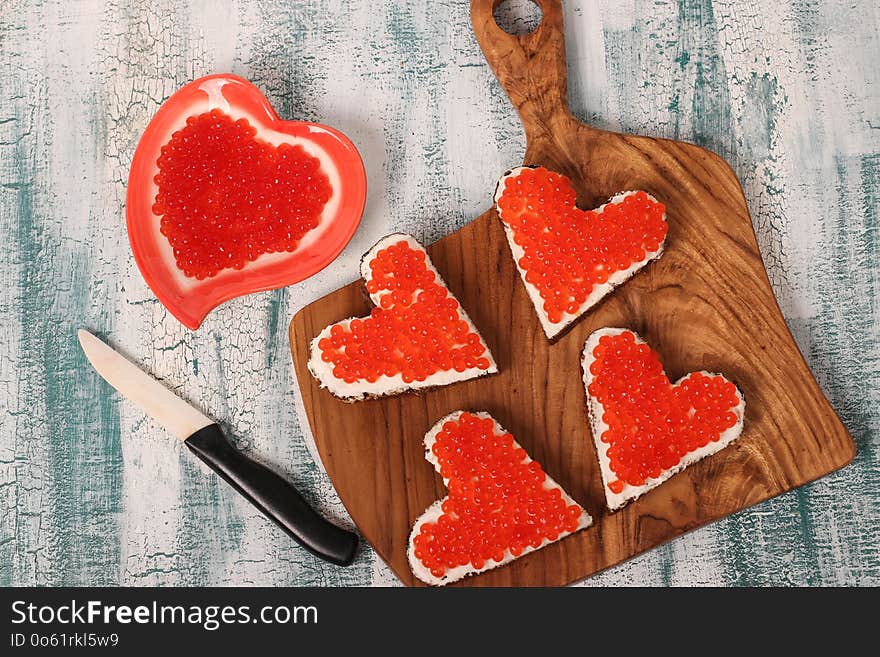 Sandwiches with red caviar and cream cheese in the shape of a heart for Valentine`s Day, top view