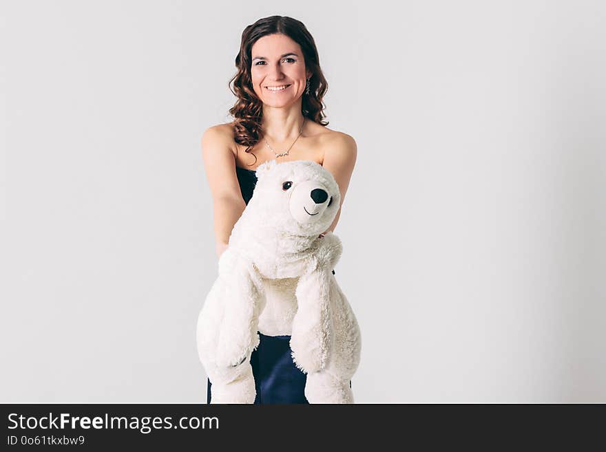 Young brunette woman in evening dress with polar bear toy on gray background isolated, concept of Valentine`s day
