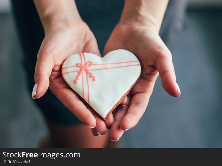 Heart white glazed gingerbread in woman hands, Valentine`s day