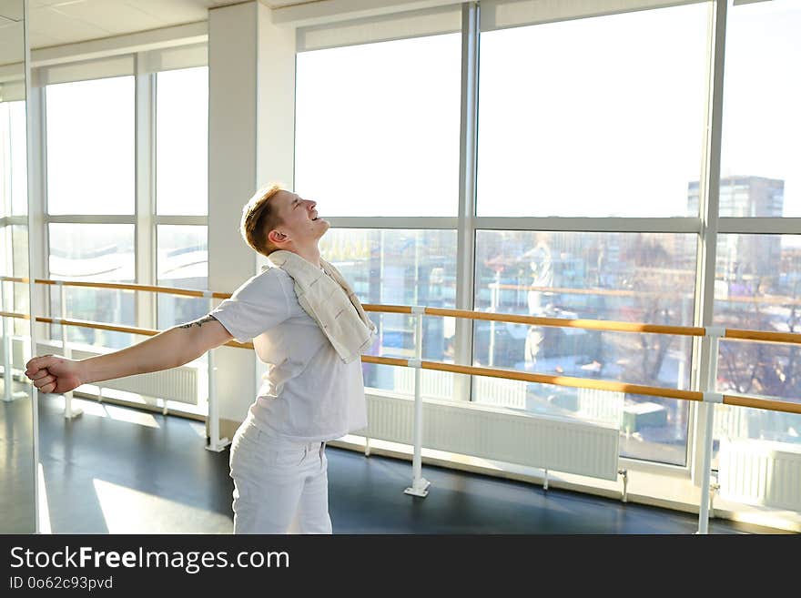 Journalist making successful attempt of standing on hands using ballet barre, tattooed fair-haired guy rejoicing at small win in sport gym. Barefoot boy wearing white T-shirt and trousers. Concept of sportswear, spacious hall or individual trainings. Journalist making successful attempt of standing on hands using ballet barre, tattooed fair-haired guy rejoicing at small win in sport gym. Barefoot boy wearing white T-shirt and trousers. Concept of sportswear, spacious hall or individual trainings