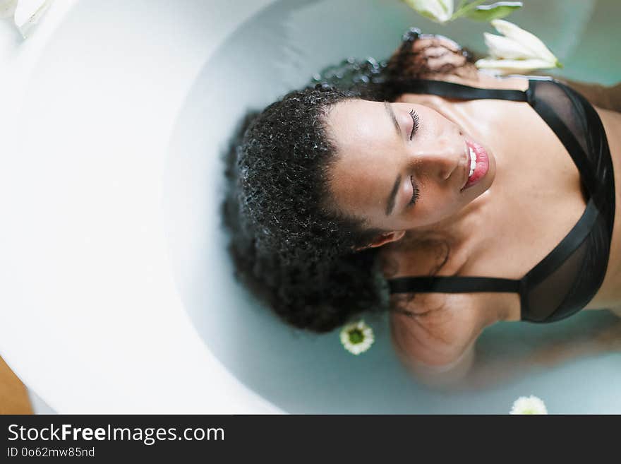 Young Relaxed Afro American Girl Taking Bath And Wearing Black Underwear, Blue Water Background.