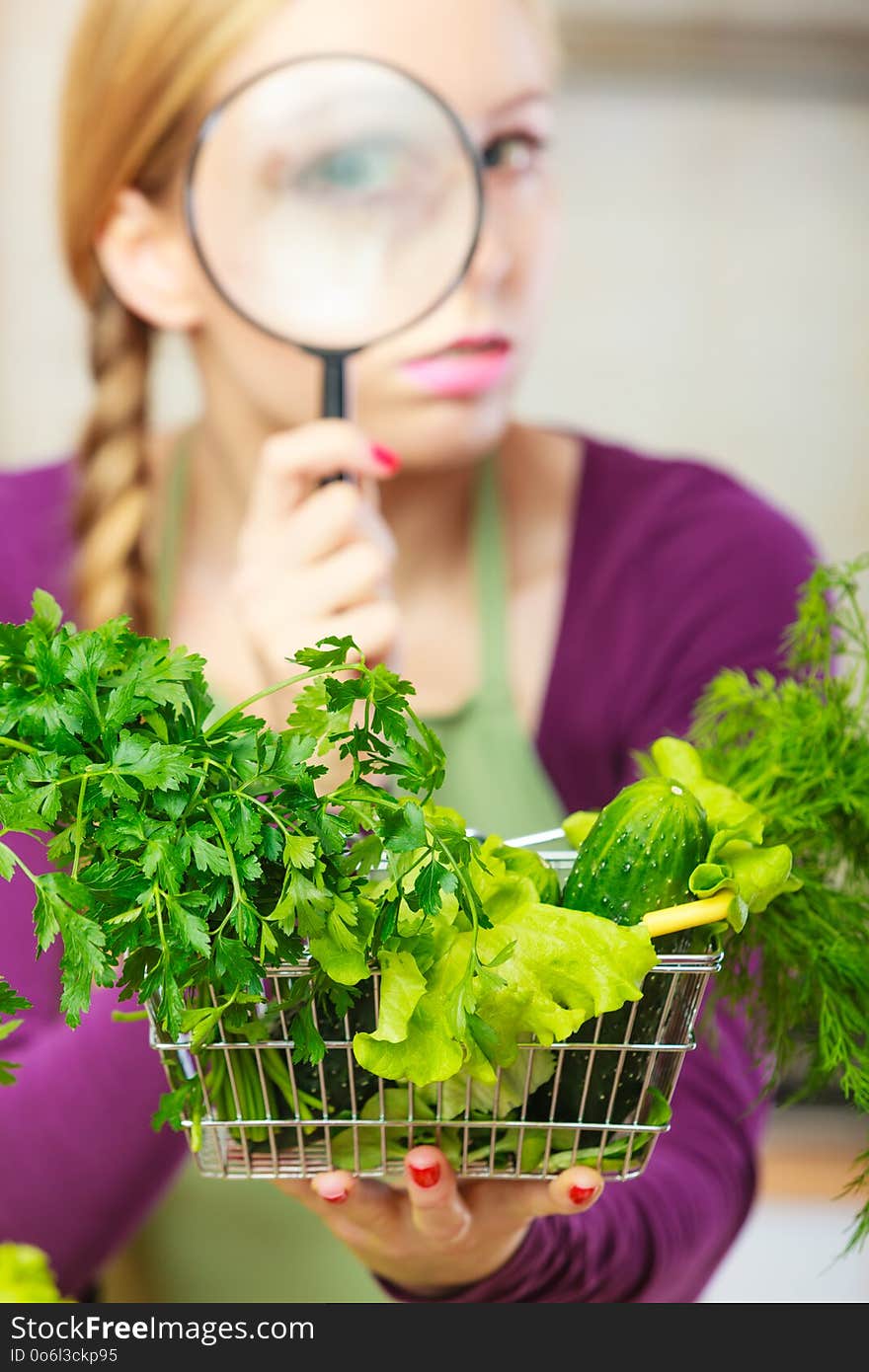 Buying healthy dieting food concept. Woman in kitchen having many green vegetables looking through magnifier at shopping basket trolley. Buying healthy dieting food concept. Woman in kitchen having many green vegetables looking through magnifier at shopping basket trolley