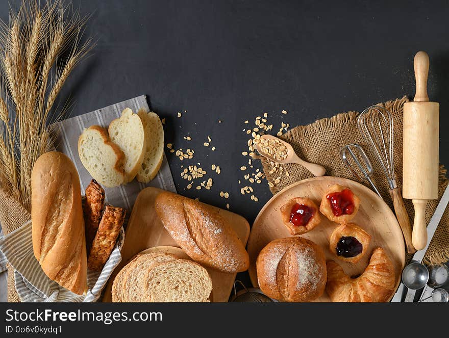 Homemade breads or bun, croissant and bakery ingredients on black stone background, breakfast food concept top view and copy space