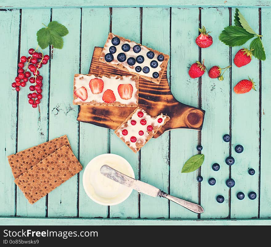 Healthy sandwiches with soft cheese and berries on bread crisps on shabby chic background. Healthy eating and summer gifts concept. Creative food