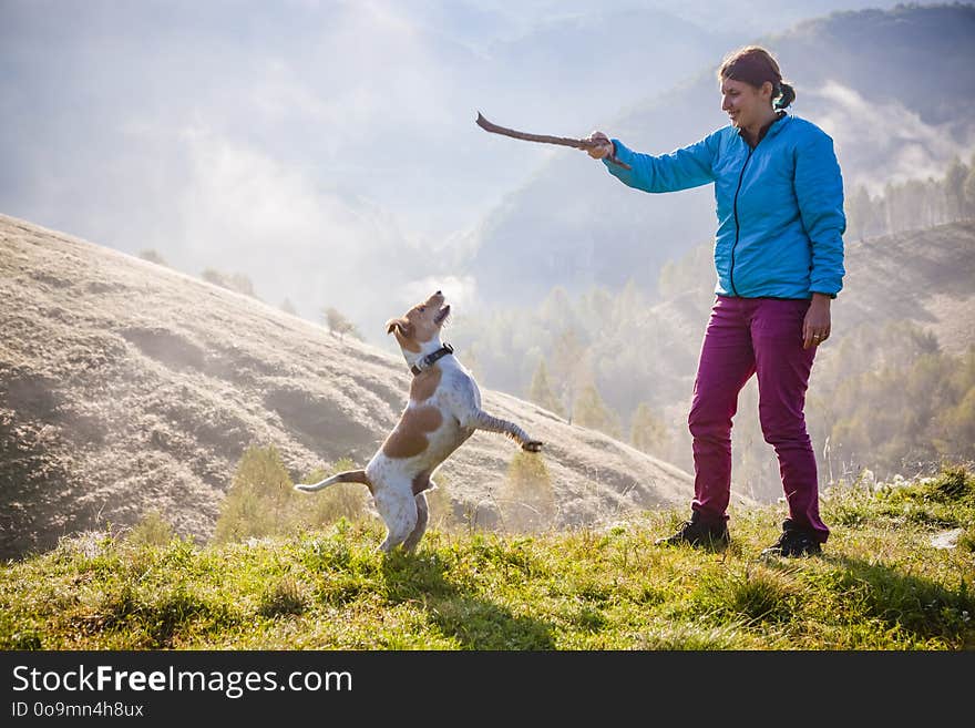 woman playing with her dog in beautiful mountain scenery in spring