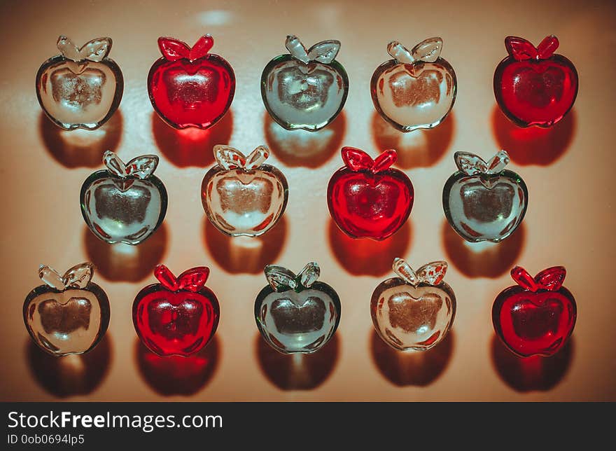 3 rows of colorful plastic transparent apples on light background top view. 3 rows of colorful plastic transparent apples on light background top view