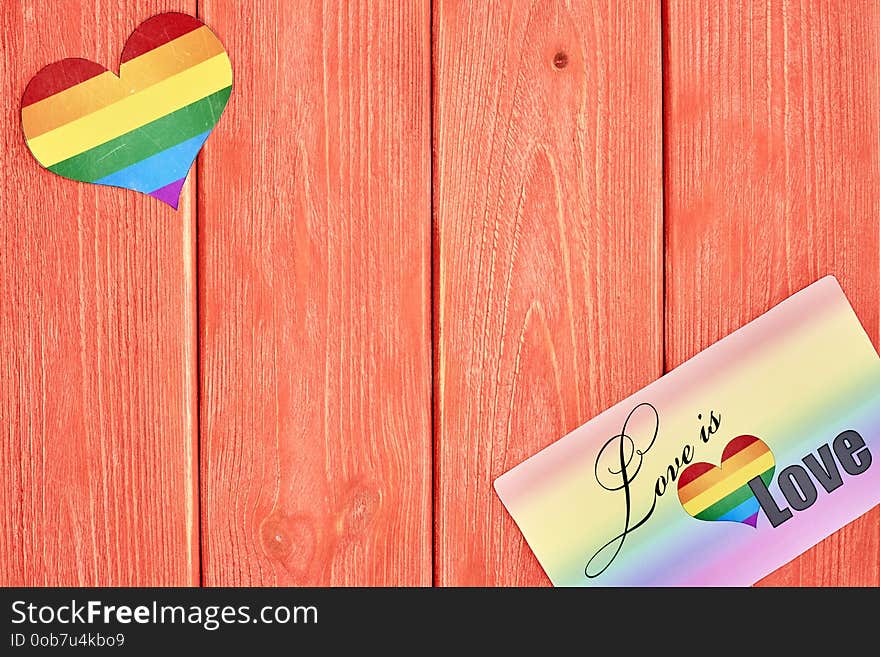 Postcard love is love and a heart with a rainbow of LGBT, on wooden texture background color living coral