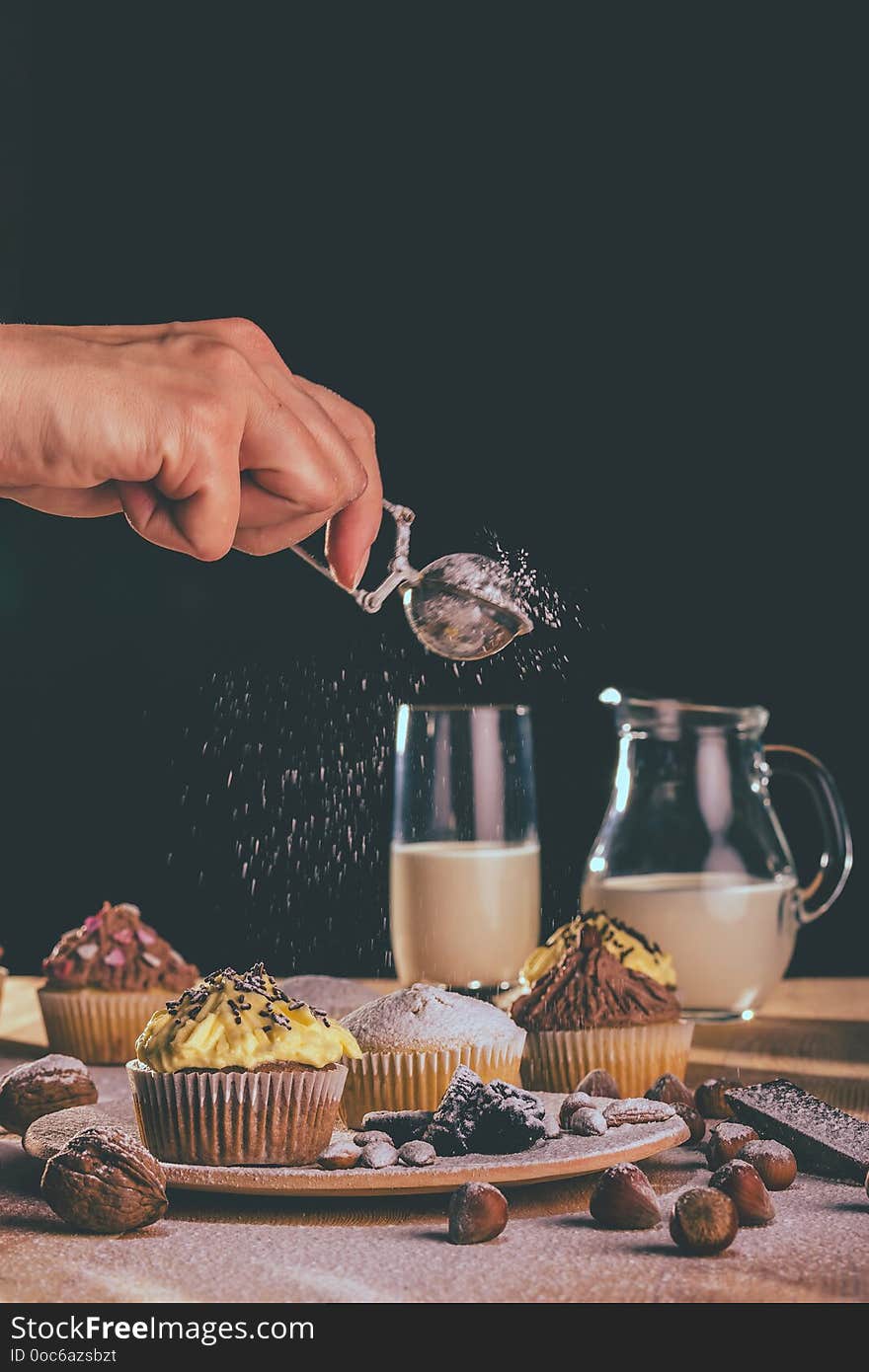 Fresh muffins and cupcakes sprinkled with sugar on a wooden board - Image