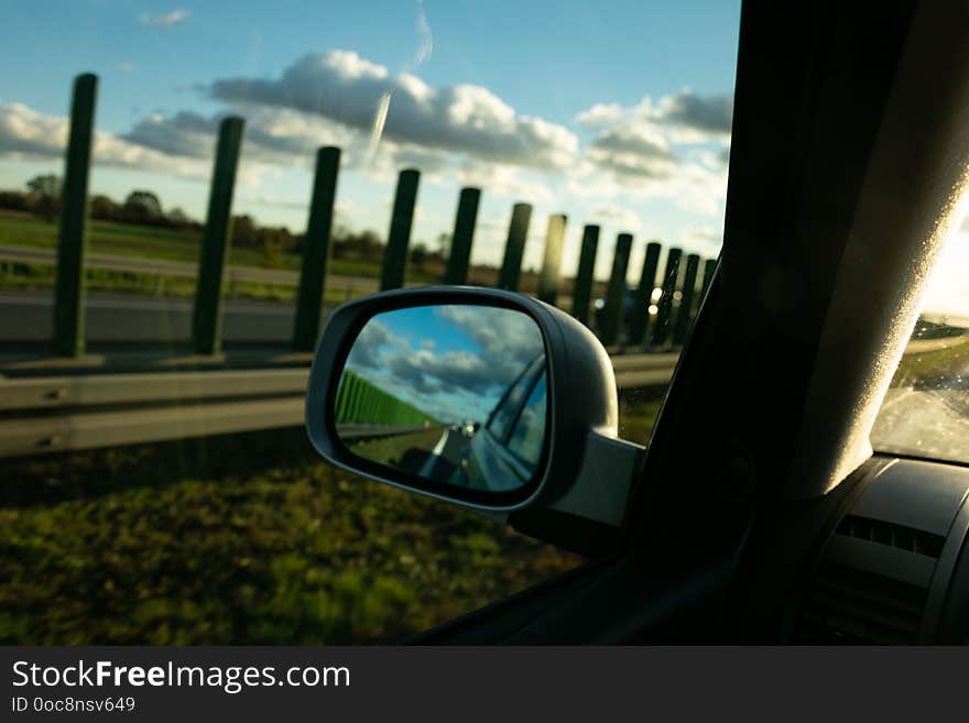 View of the highway in the rear-view mirror, in the background of the sunset. View of the highway in the rear-view mirror, in the background of the sunset