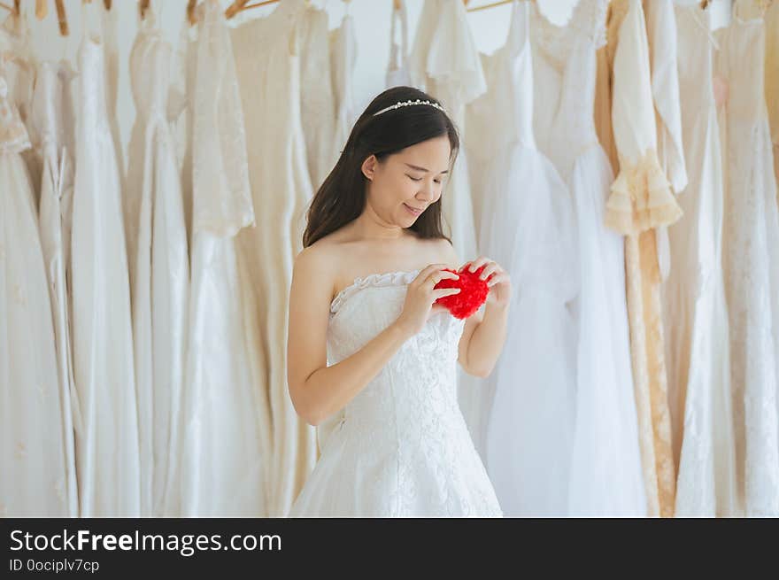 Happy young beautiful bride asian woman smiling and hand holding model red heart