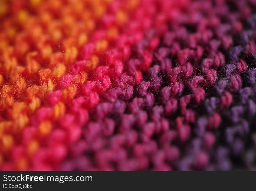 Macro photograph of seamless knitted diagonal patterns in vivid rainbow mixed colors with primary orange and purple with shallow selective focus for abstract look. Concept: Knitting passion. Macro photograph of seamless knitted diagonal patterns in vivid rainbow mixed colors with primary orange and purple with shallow selective focus for abstract look. Concept: Knitting passion