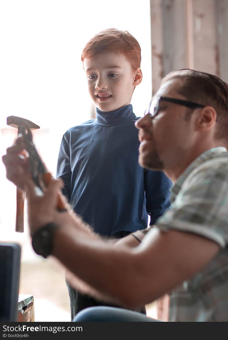 Close up.father teaches his son to use a hammer for household work