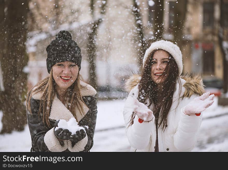 Two best female friends play with snow. Winter outdoor activities, positive emotions, joy and happiness