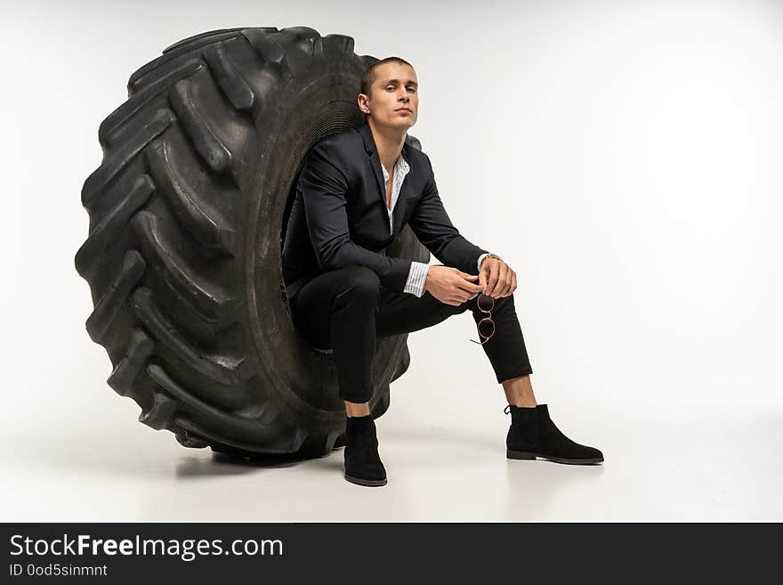 Stylish Handsome Man In Black Suit Sitting In Tire