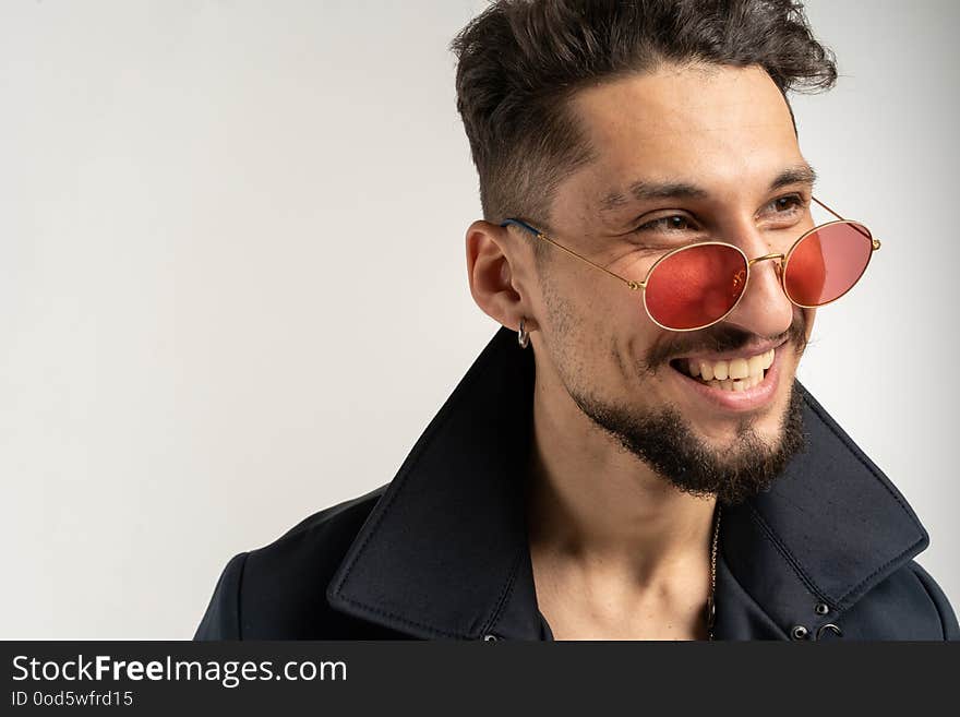 Close up portrait of smiling handsome man in sunglasses in black jacket on white background