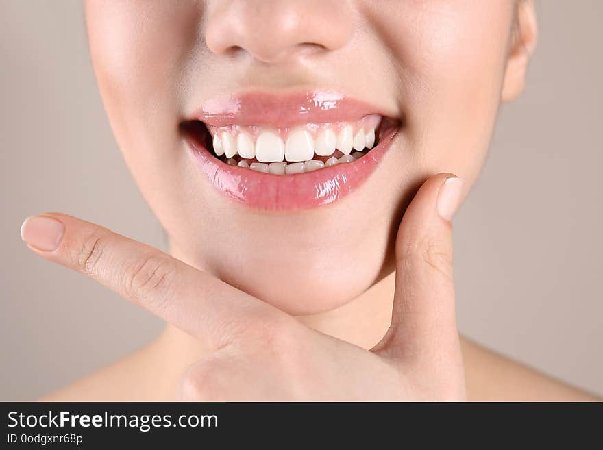 Beautiful young woman with healthy teeth on color background