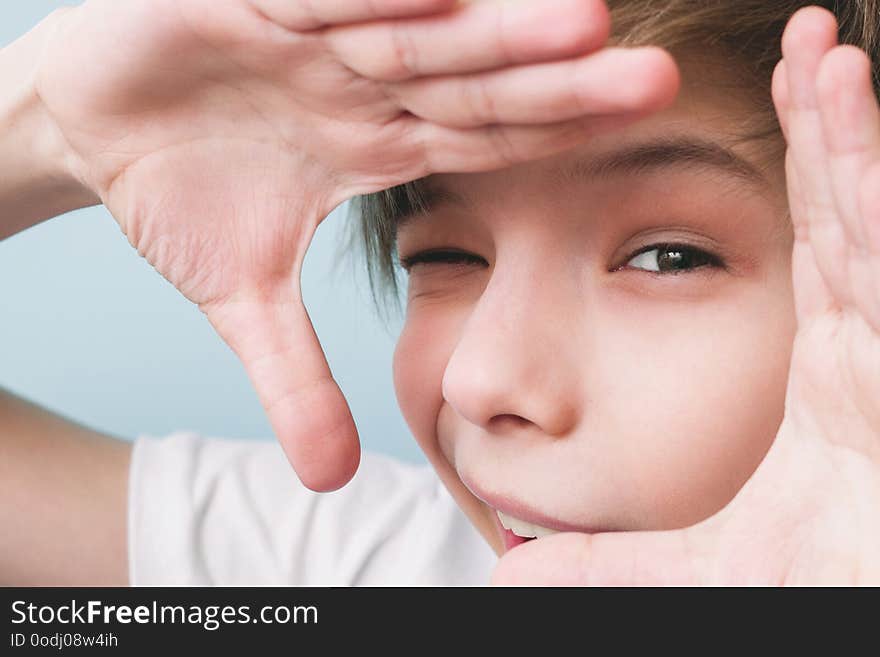 Cheerful boy shows frame with his hands