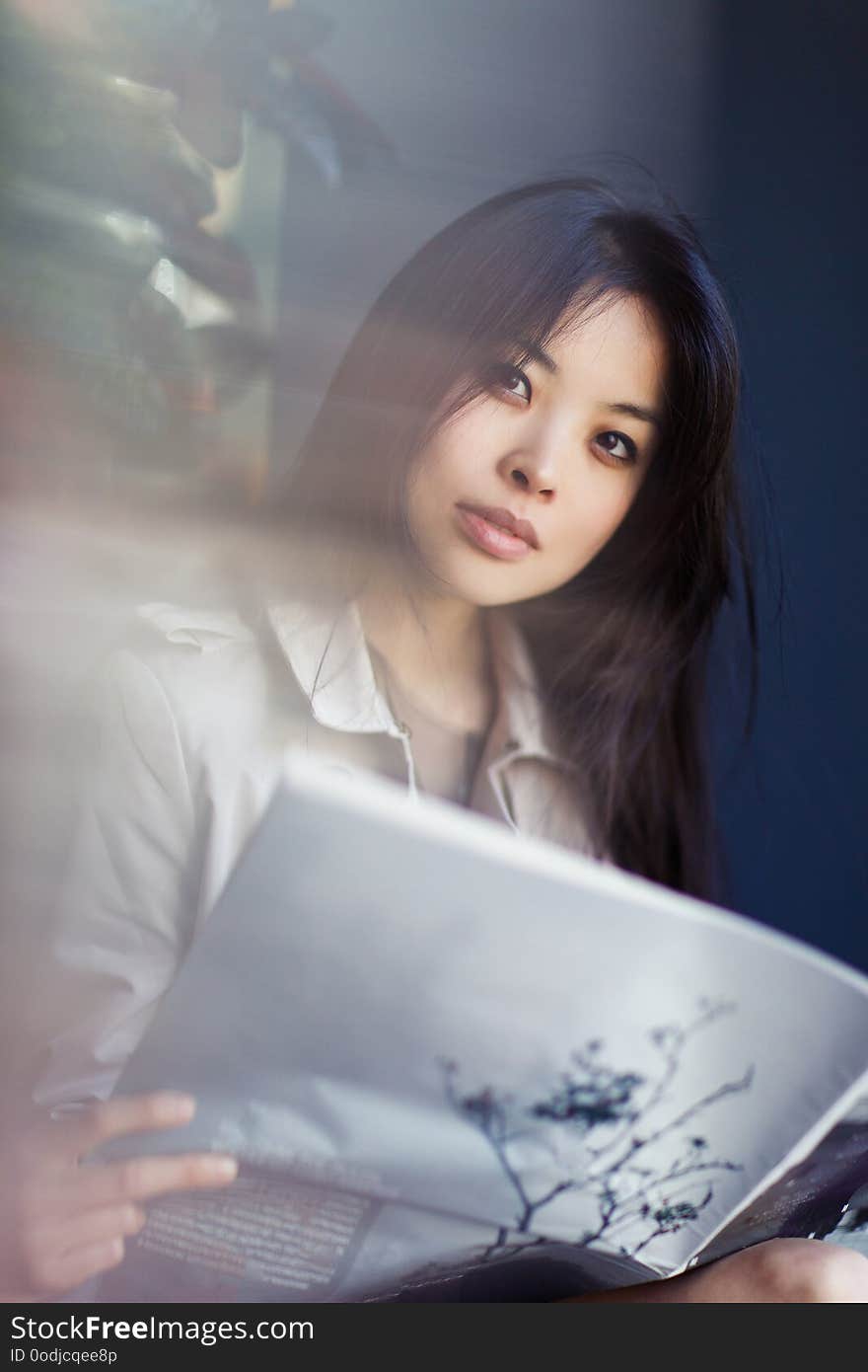 Portrait of young brunette with magazine on blurred background