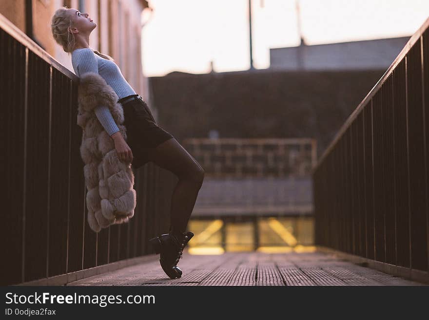 Photo Side Of Blonde In Fur Vest On Walk On Bridge