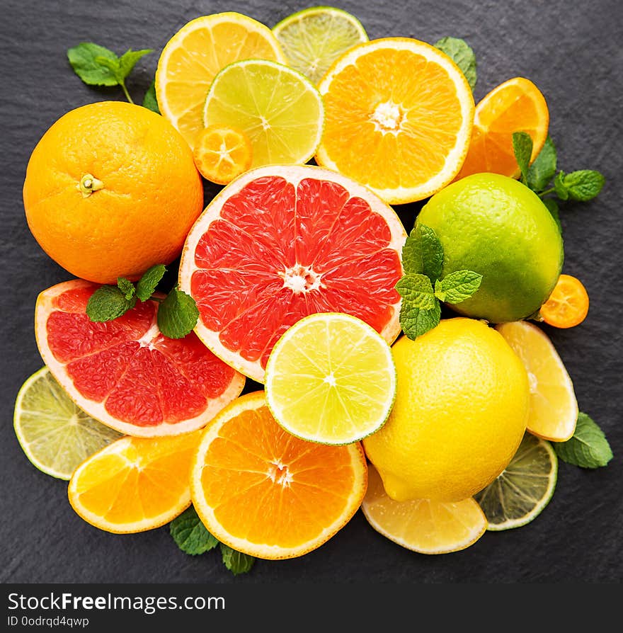 Fresh citrus fruits on a black stone background