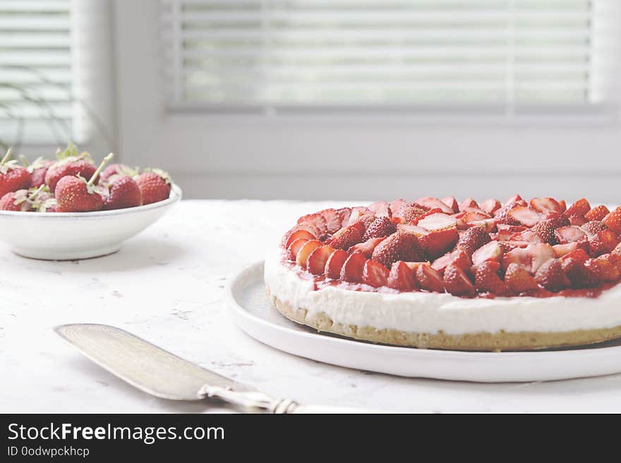 Strawberry cheesecake on white table near window. Selective focus. Haze effect