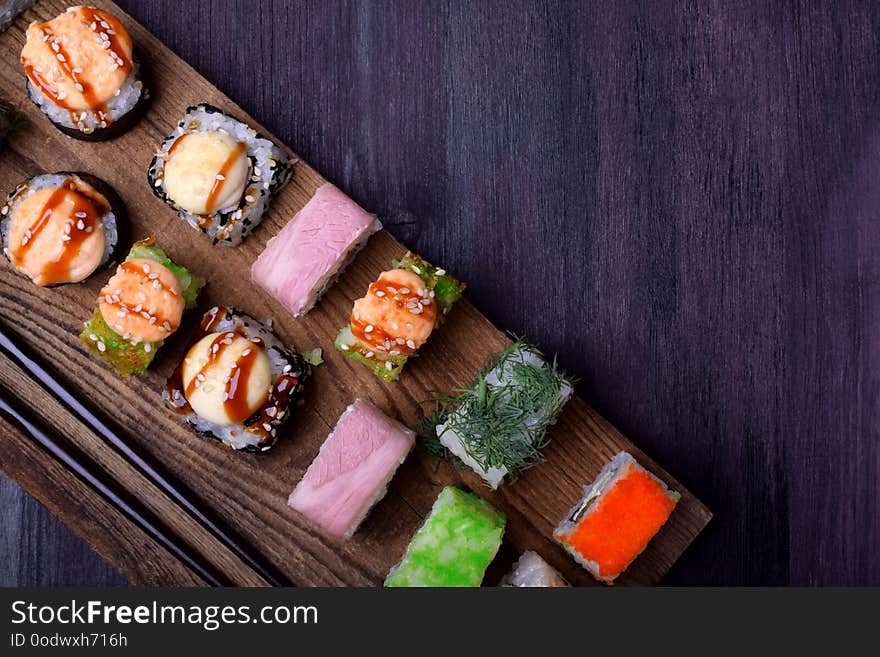 Assortment of baked and fresh sushi rolls on a wooden board. Japanese cuisine