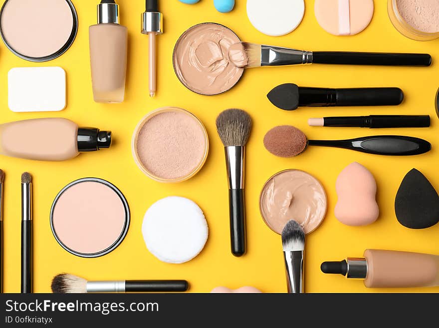 Flat lay composition with skin foundation, powder and beauty accessories on color background