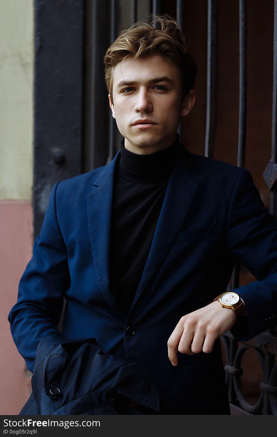 Portrait of an attractive man in a suit and a black sweater, close-up, on his hand a gold watch,brooding pose, looking at the camera.