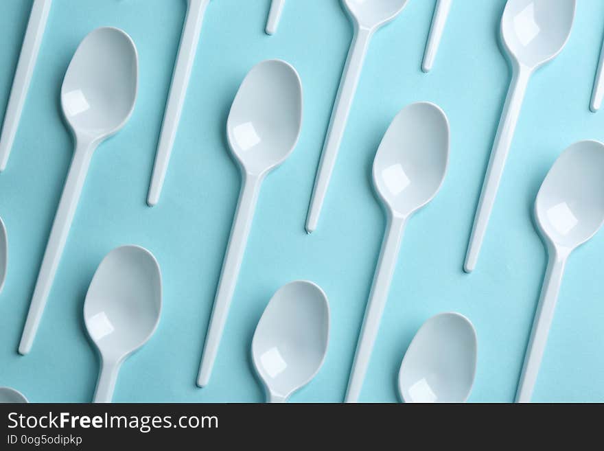 Flat lay composition with plastic spoons on color background