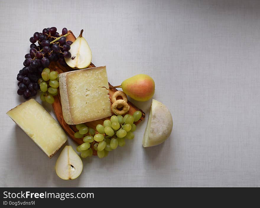 Italian cheese with pears and grapes on wooden cutboard, white background, place for text