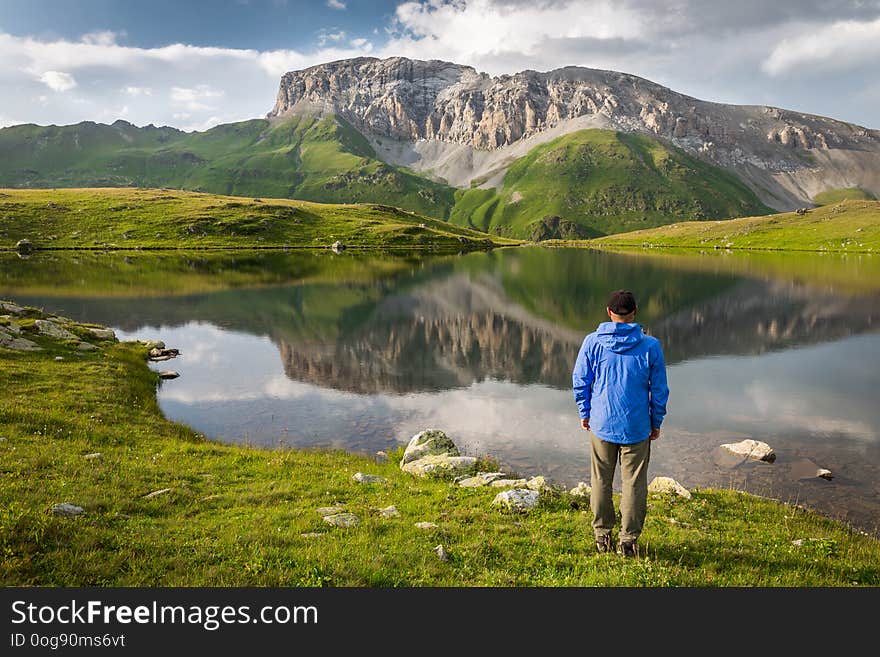 Traveler around the mountain lake and rocky peak. Adventure, travel, tourism and hike concept. Traveler around the mountain lake and rocky peak. Adventure, travel, tourism and hike concept