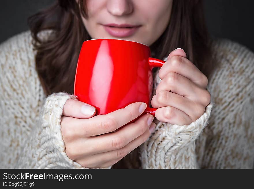 Girl in a light sweater holding a red cup of coffee