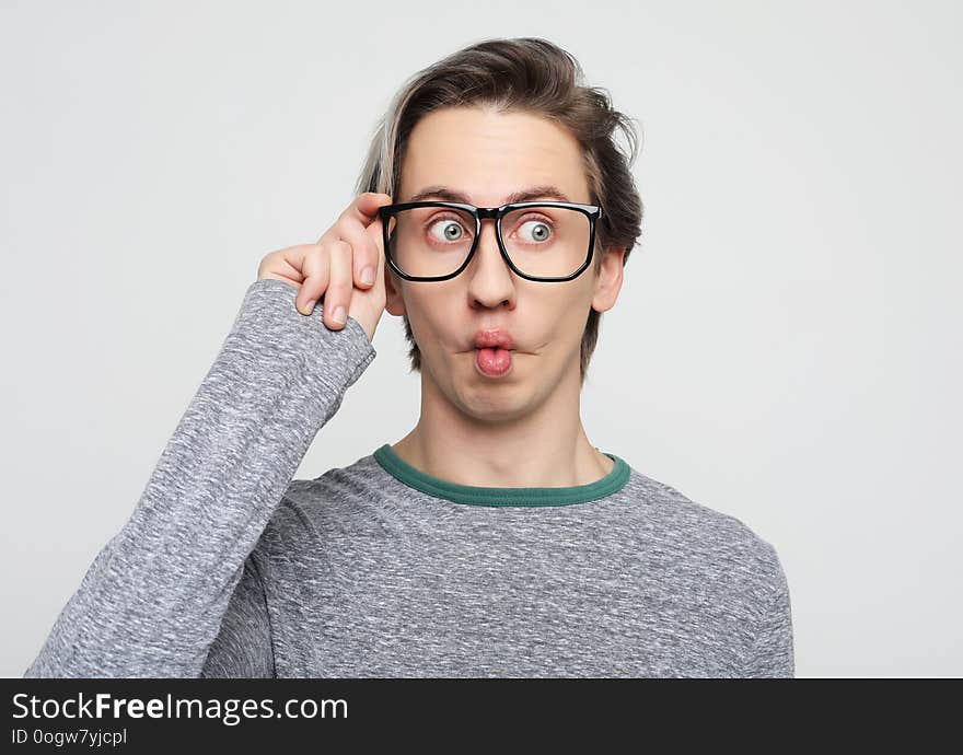 Young attractive man wearing yellow sweater astonished and amazed in shock and surprise face expression isolated on white background