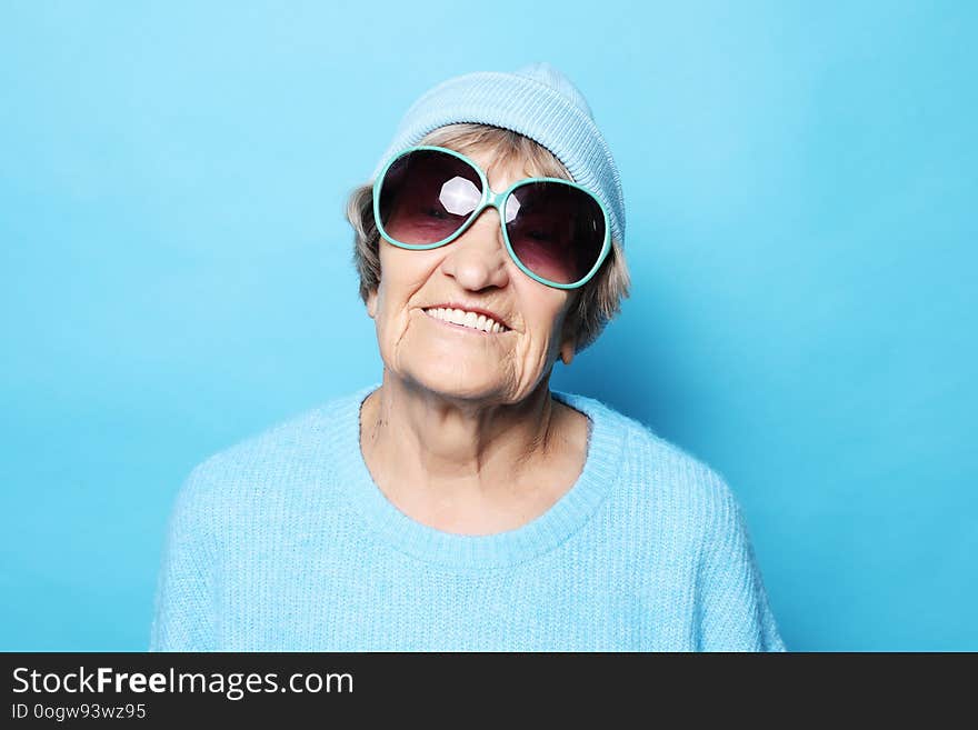 Funny happy grandmother wearing blue sweater and sunglasses