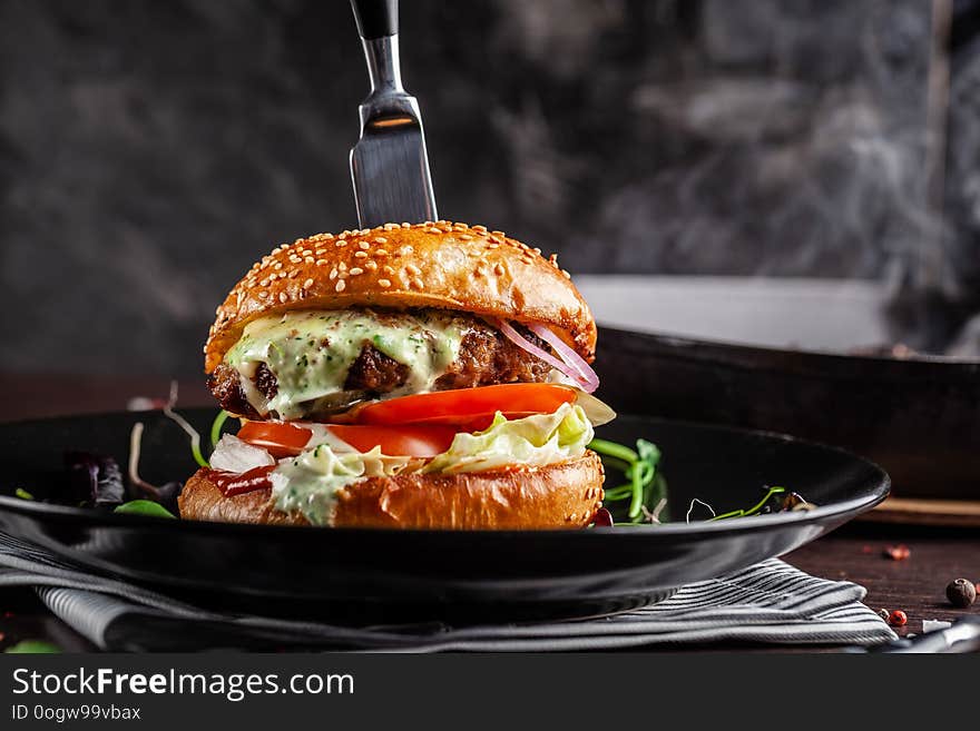 American cuisine concept. A juicy meat burger with a large klateyta, tomato, cucumber, ketchup and salad. Cooking burgers at home. Background image for a menu in restaurants or cafes. copy space
