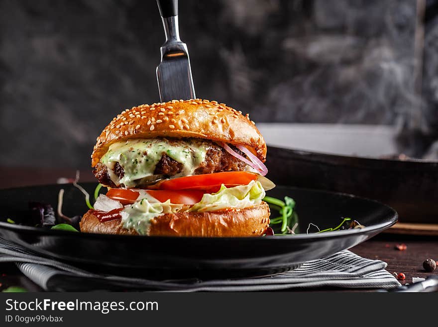 American cuisine concept. A juicy meat burger with a large klateyta, tomato, cucumber, ketchup and salad. Cooking burgers at home