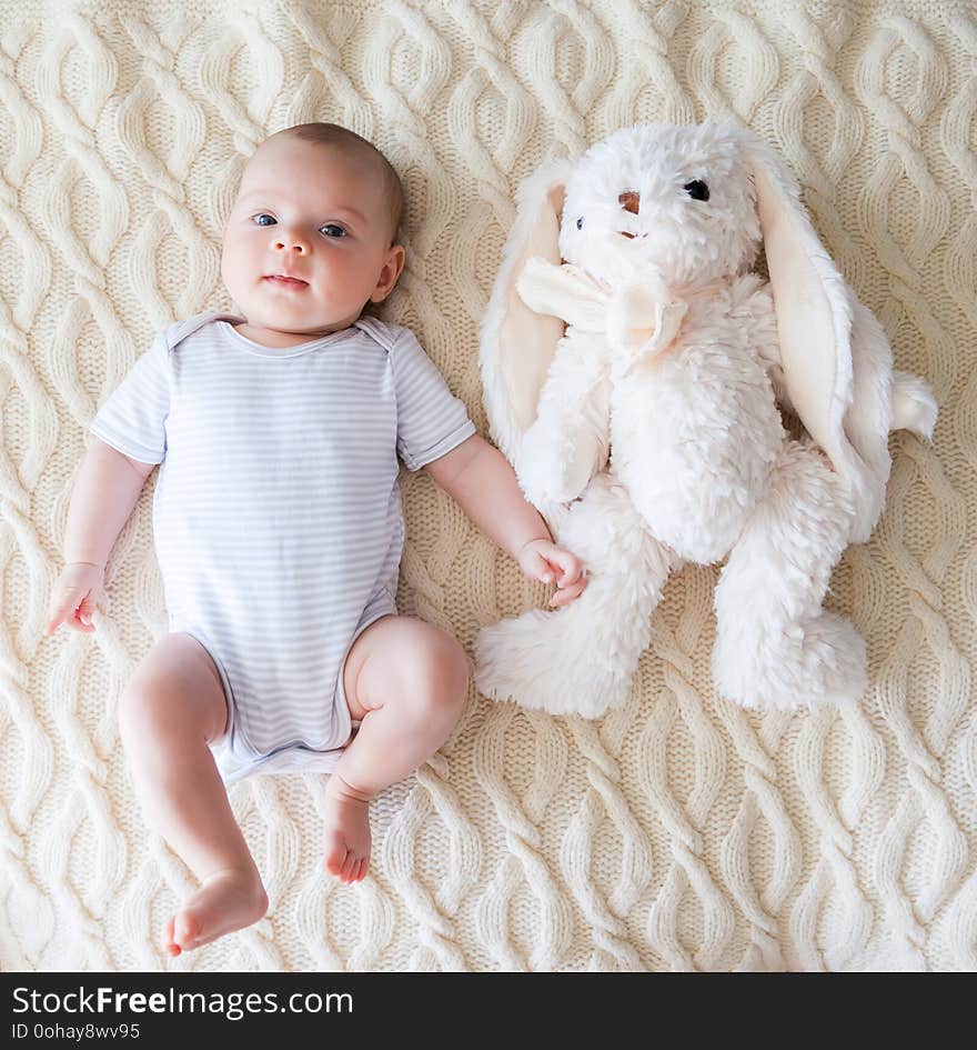 Cute baby girl lying on her back with white rabbit toy. Cute baby girl lying on her back with white rabbit toy