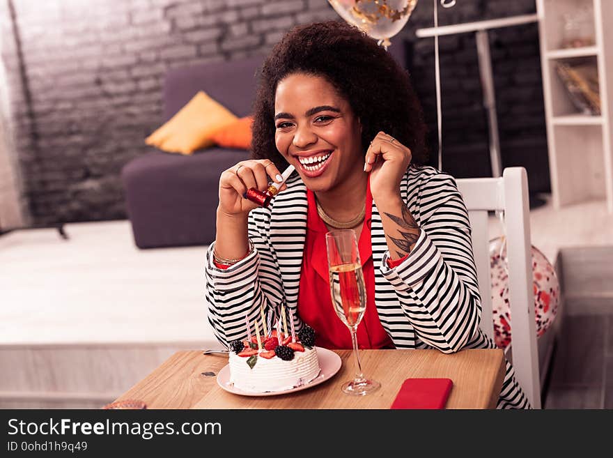 So much fun. Joyful nice woman sitting in front of the cake while enjoying her birthday party. So much fun. Joyful nice woman sitting in front of the cake while enjoying her birthday party