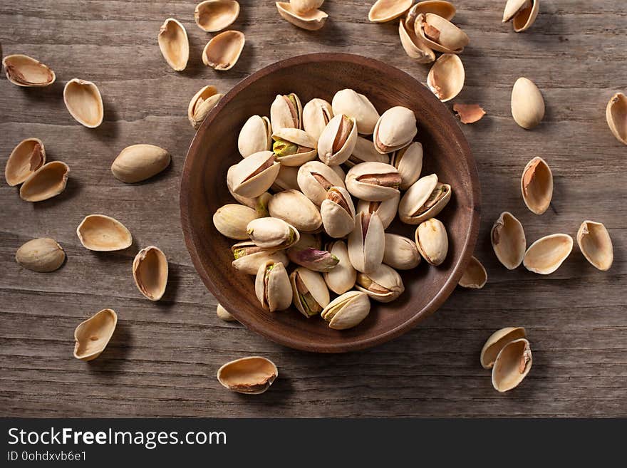 Pistachio nuts whole with husks cracked open on wooden table. Pistacia vera. Pistachio nuts whole with husks cracked open on wooden table. Pistacia vera