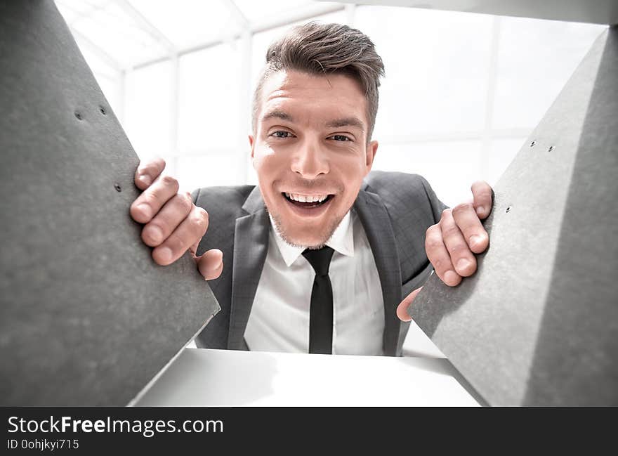 Businessman in the background smiling and holding documents that stand on a shelf in a cabinet